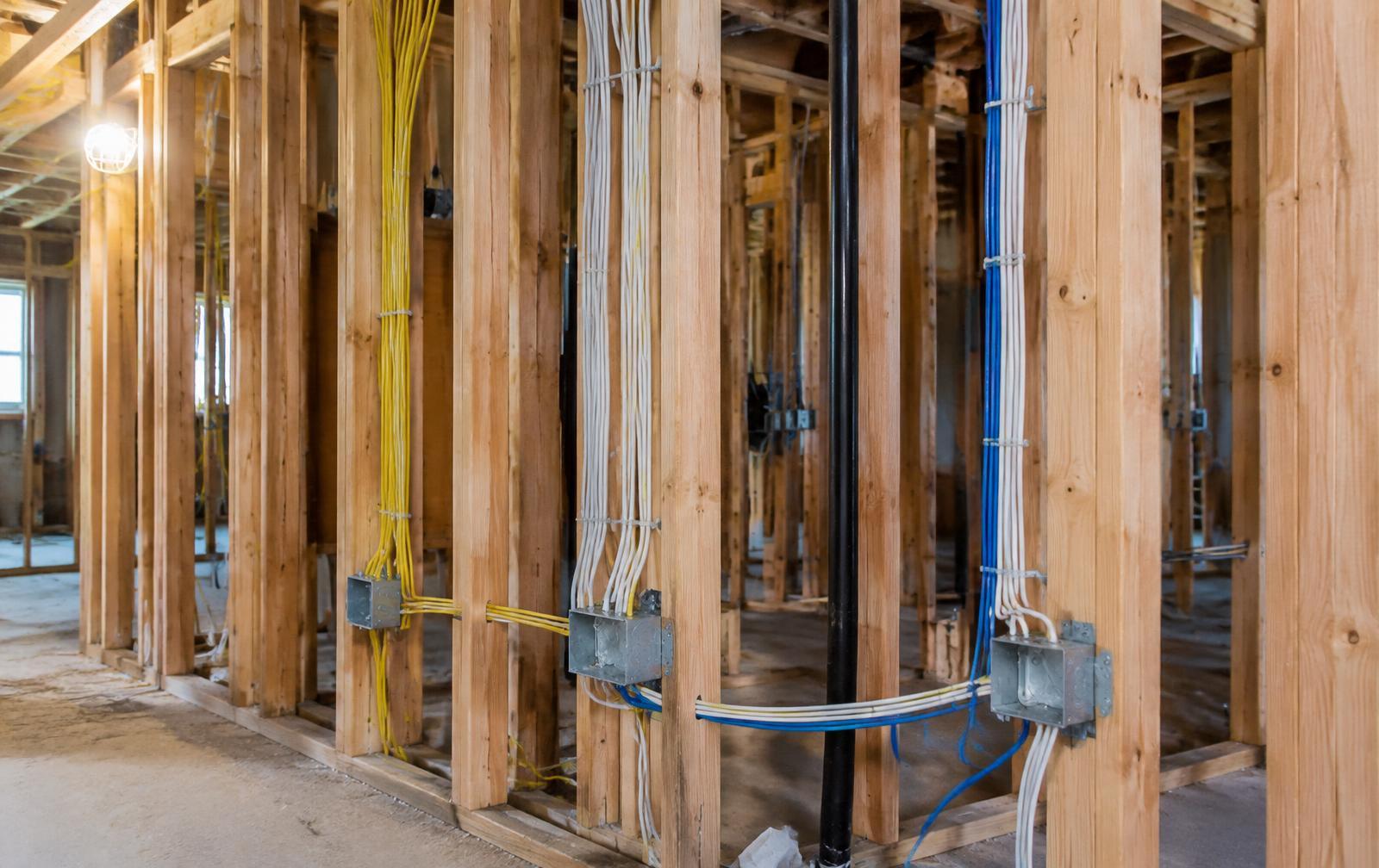 New electrical cables and junction boxes run through wood wall framing during construction